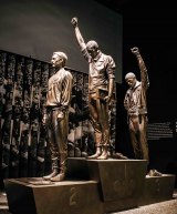 Tommie Smith (center on stand) in an iconic statue on display at the National Museum of African American History and Culture in Washington D.C